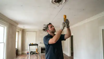 New Orleans electrician marks ceiling joists for recessed lighting installation with a stud finder and chalk line.