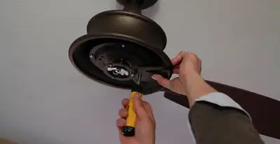 Electrician installing ceiling fan mounting bracket and fixture in New Orleans, LA