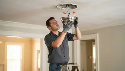 Electrician installing and wiring a ceiling light fixture in a New Orleans, LA home
